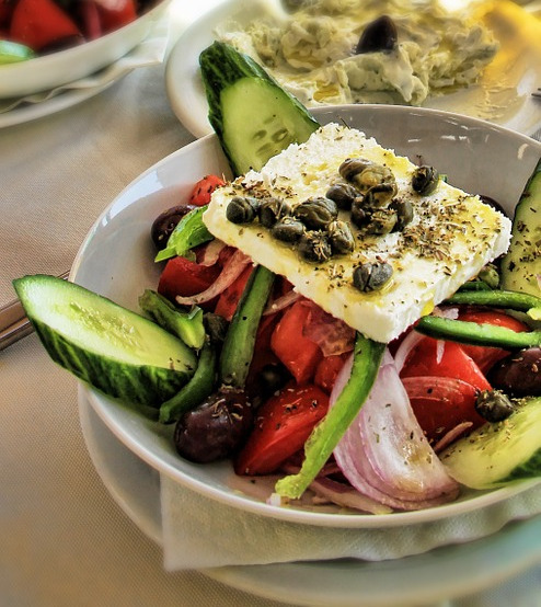 Santorini traditional salad with capers and caper leaves, cherry tomatoes, local crunchy cucumber “katsouni” & fresh made Santorini goat cheese “chloro”